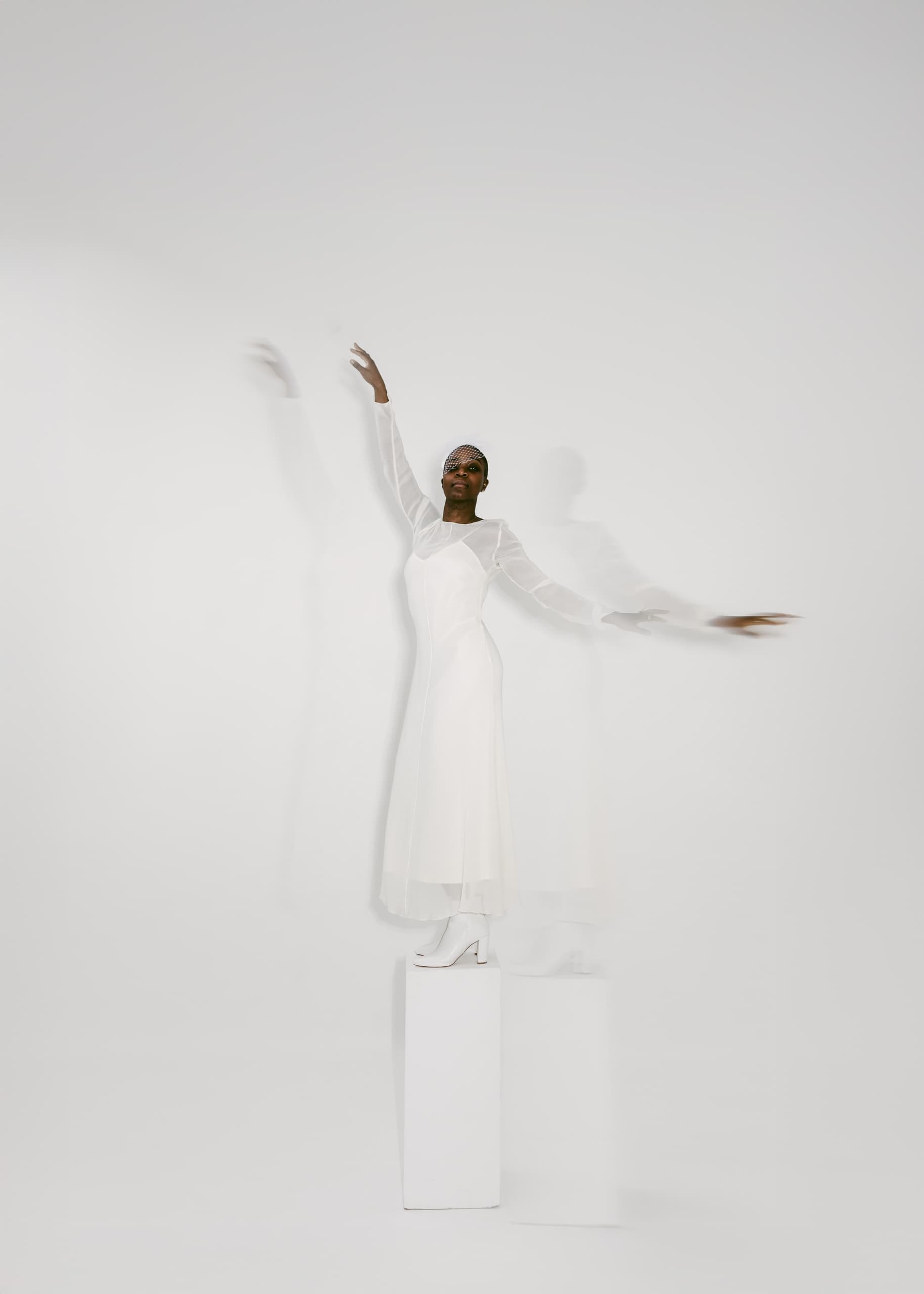 Elegant figure in white dress with dynamic pose on pedestal.