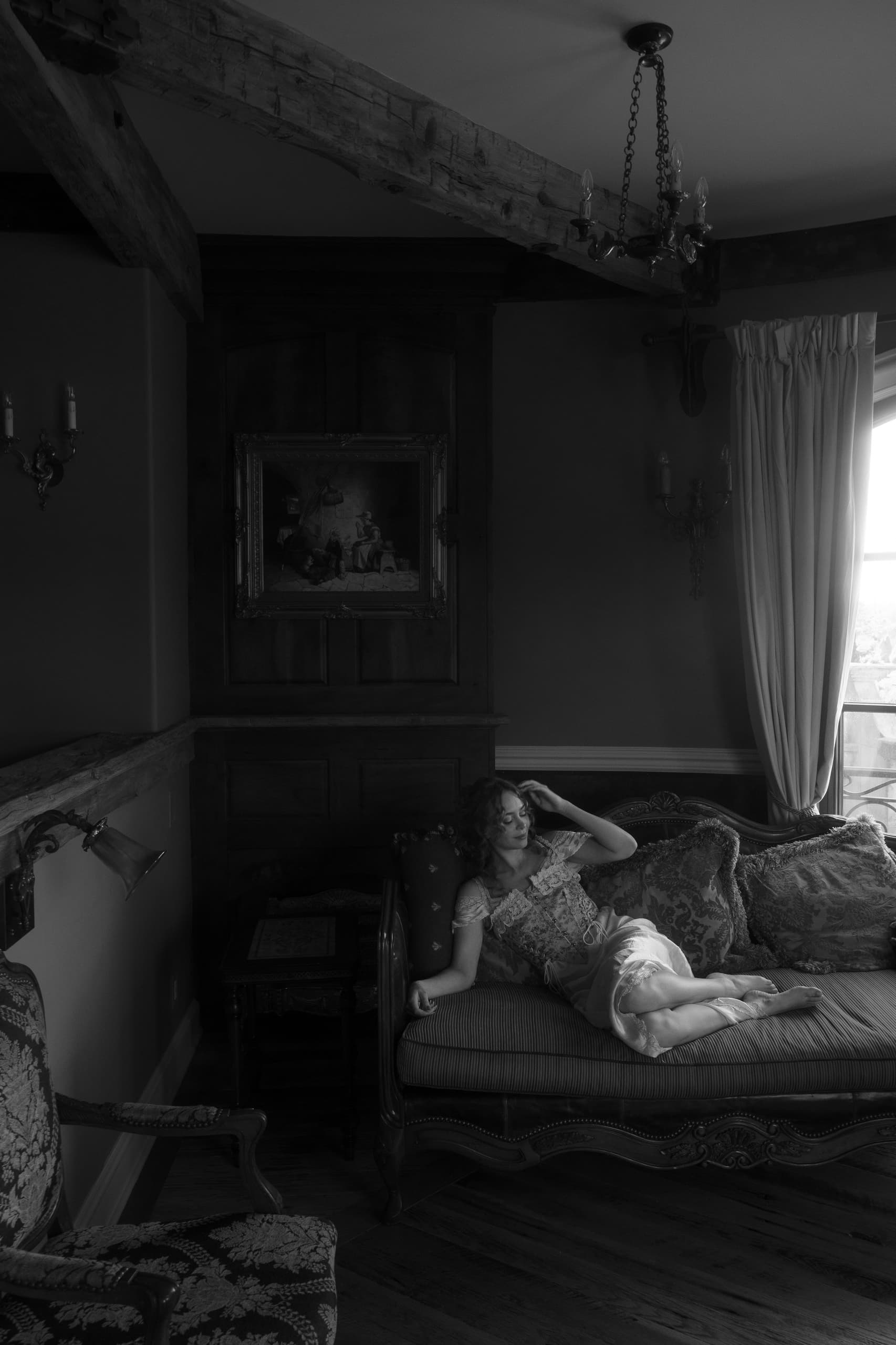 Woman relaxing on a vintage couch in a classic, dimly lit living room.