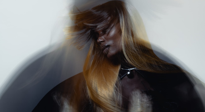 Woman with flowing hair in motion, dreamy blur effect, artistic portrait.