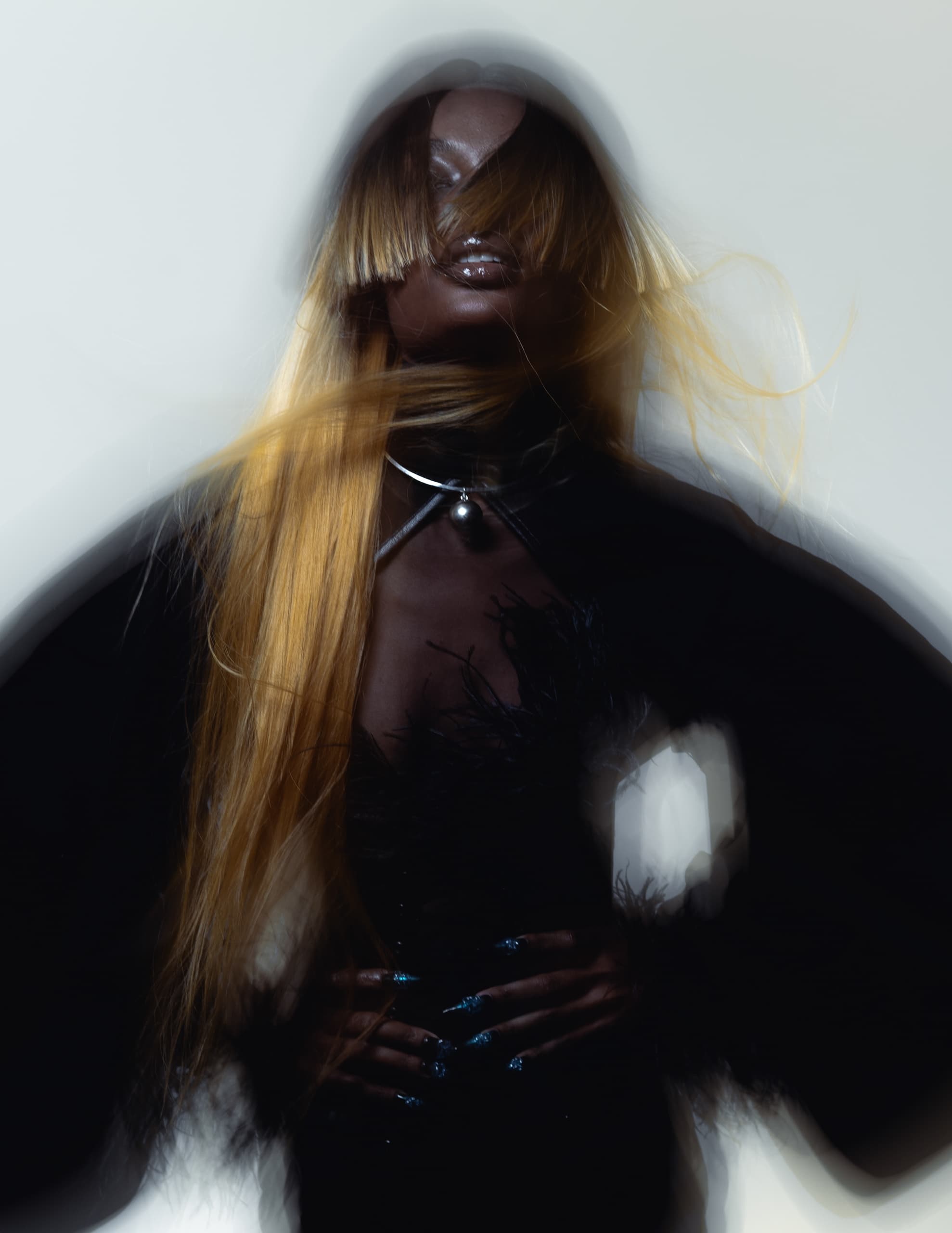 Mysterious figure with flowing hair, abstract styling, and dramatic fashion elements.