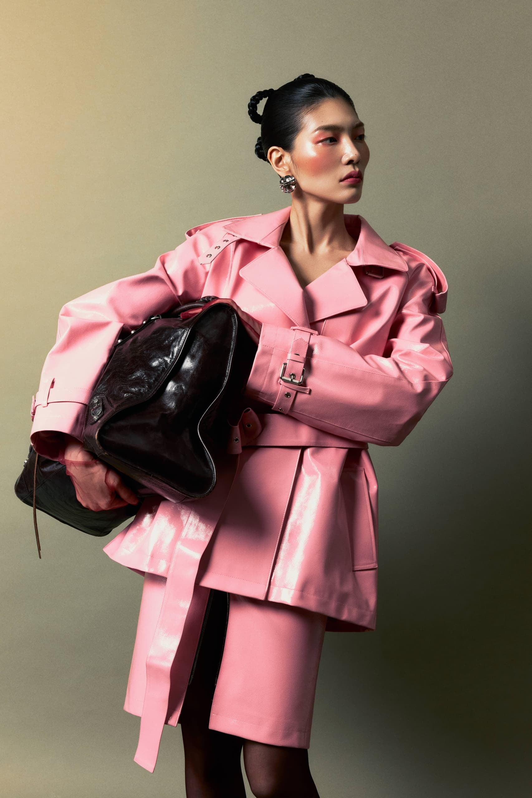 Model in stylish pink coat with oversized black bag. Fashion editorial pose.
