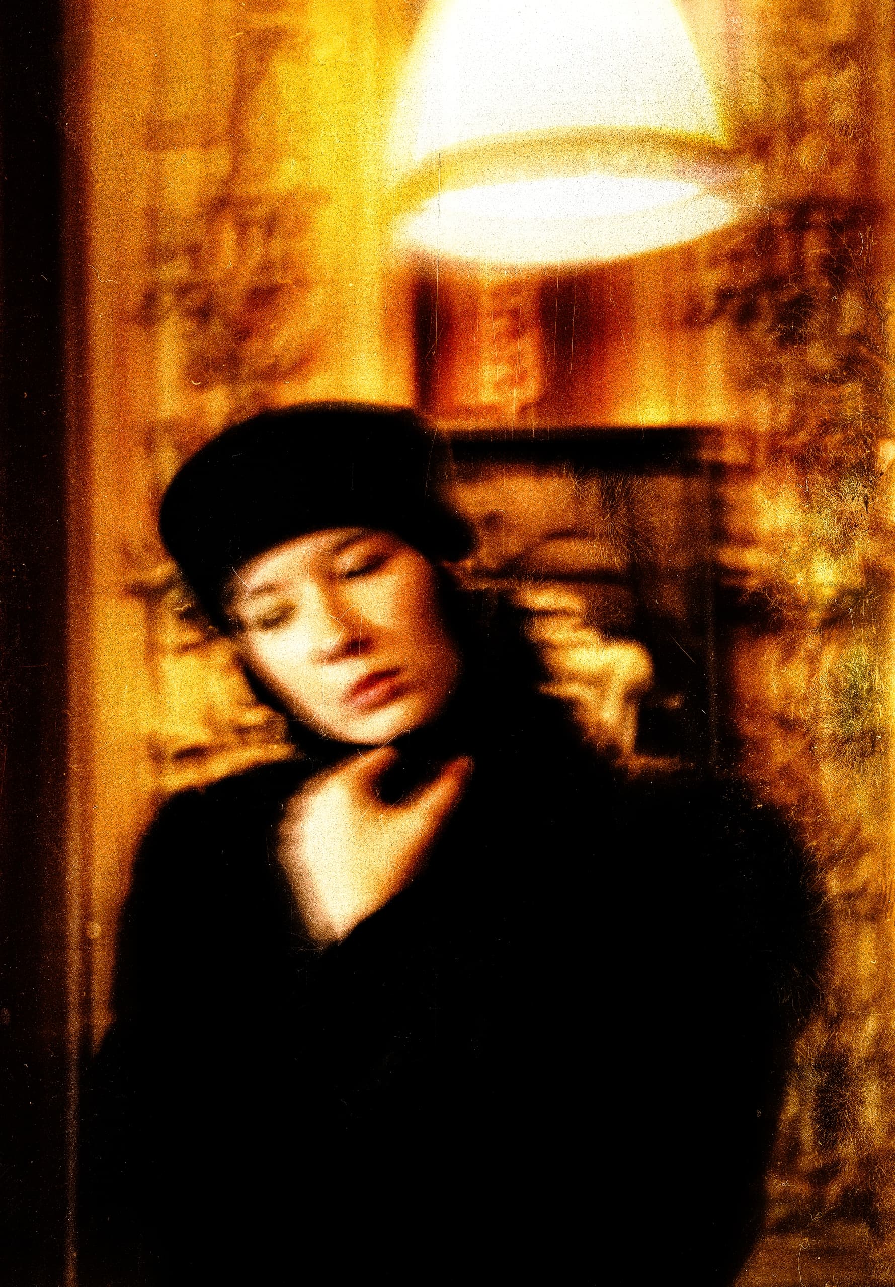 Vintage-style blurry portrait of a person in a black hat and soft lighting.