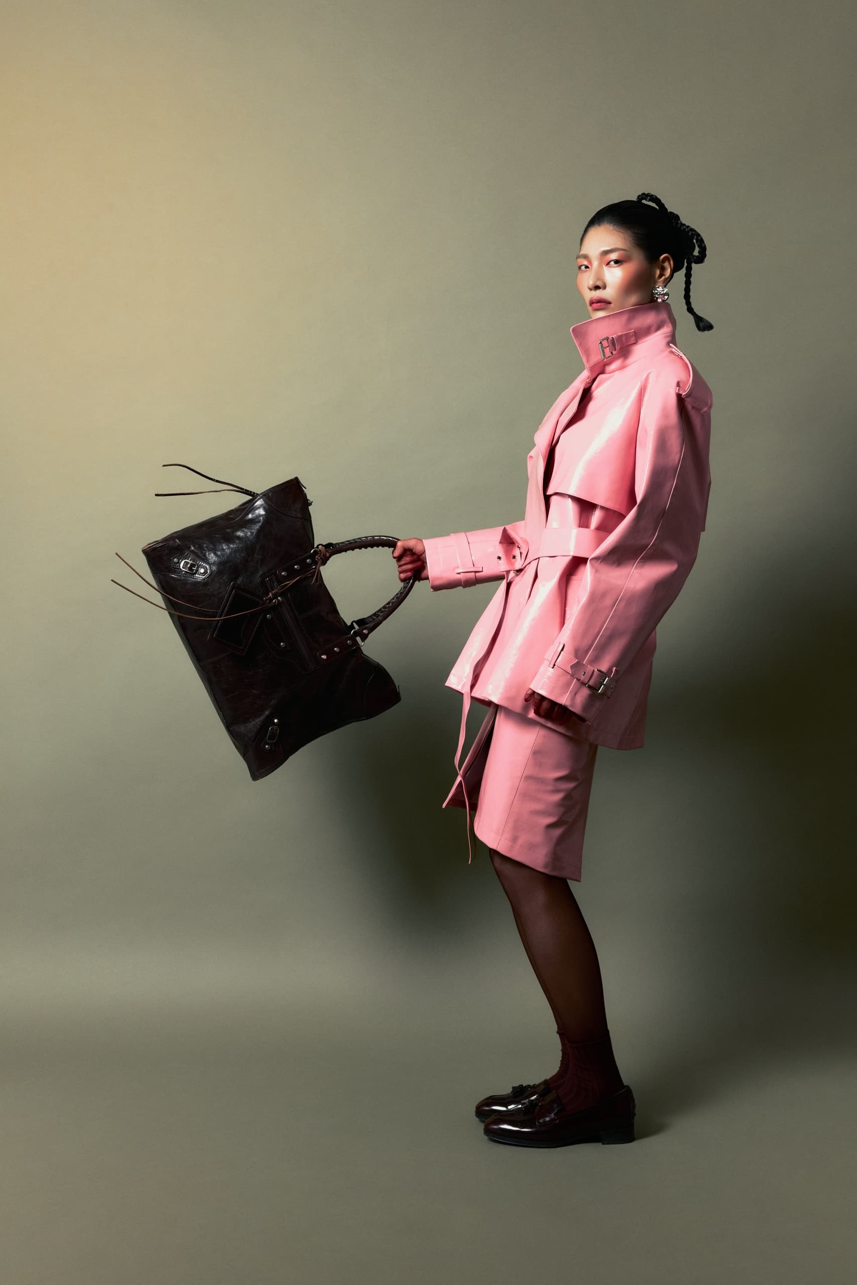 Person in pink outfit holding large brown designer bag.