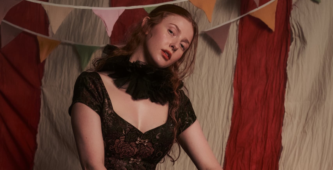 Woman in vintage dress with ruffled collar in front of colorful party bunting.