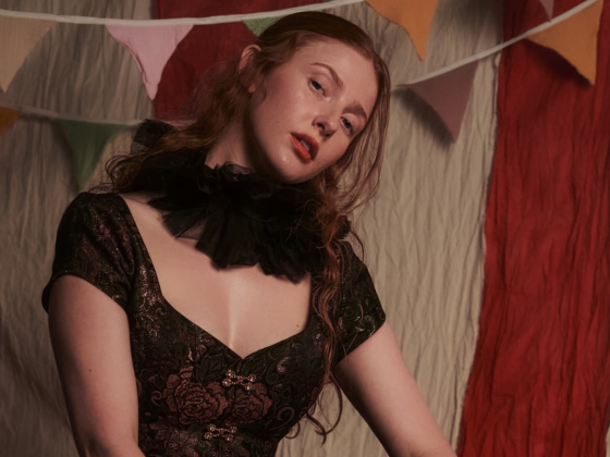 Woman in vintage dress with ruffled collar in front of colorful party bunting.