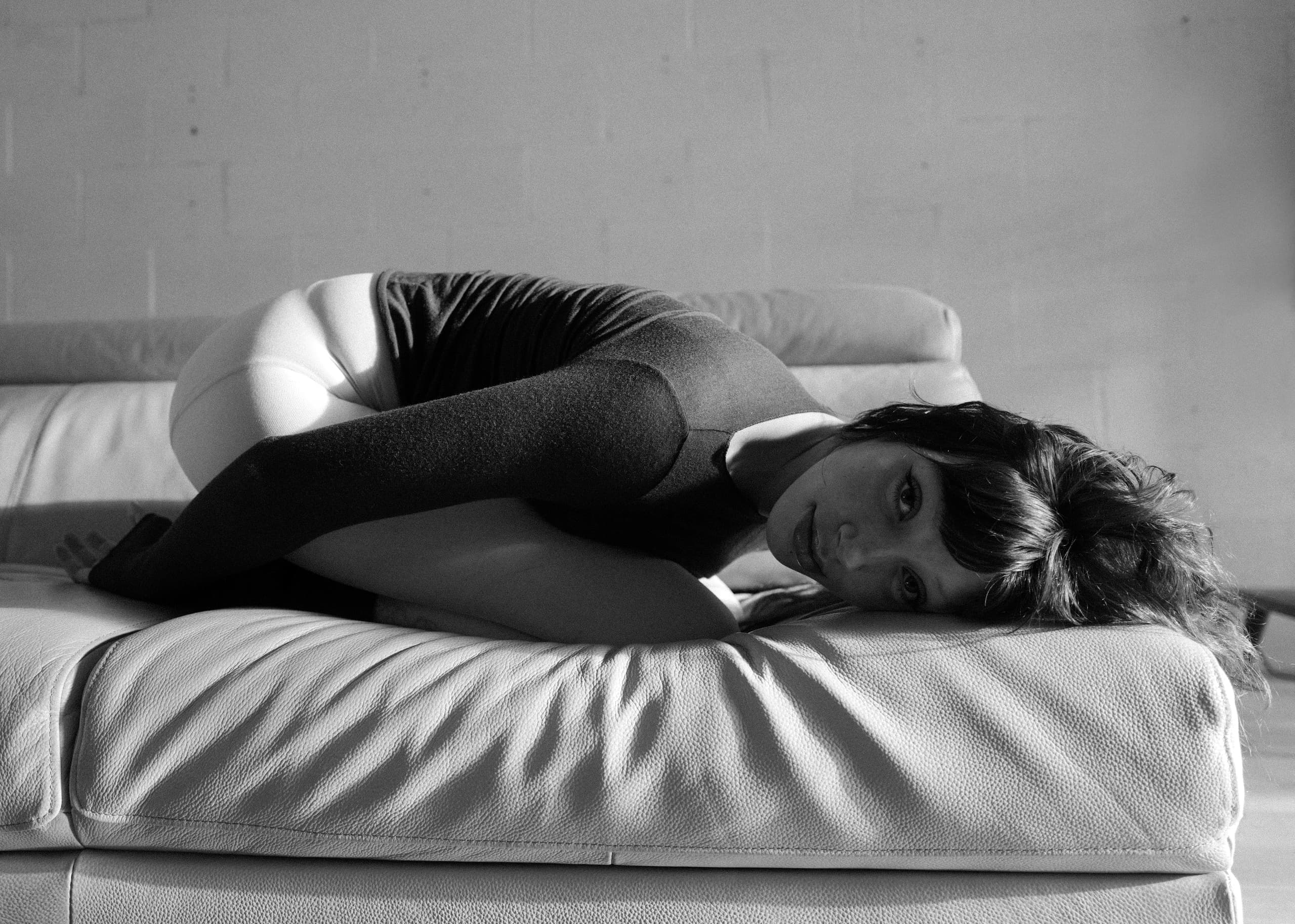 Black and white photo of a woman lying on a couch, gazing thoughtfully.