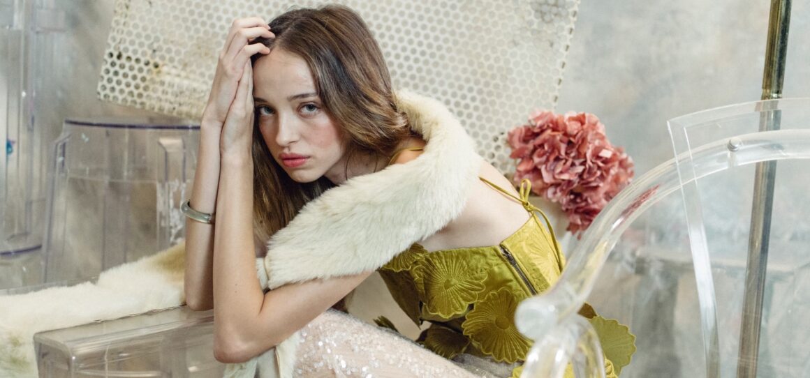Fashionable woman in elegant floral dress seated pensively.