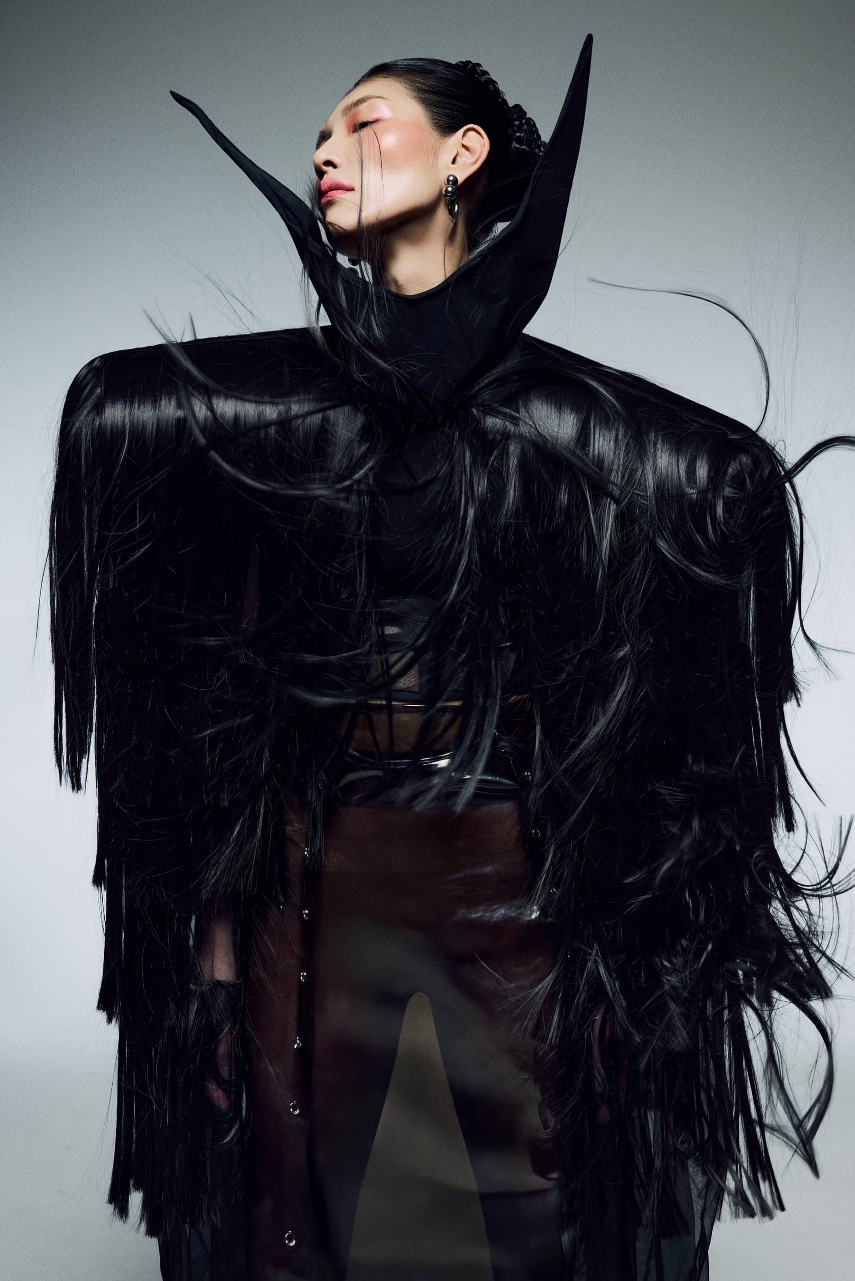 Avant-garde fashion with dramatic black outfit and fierce expression.