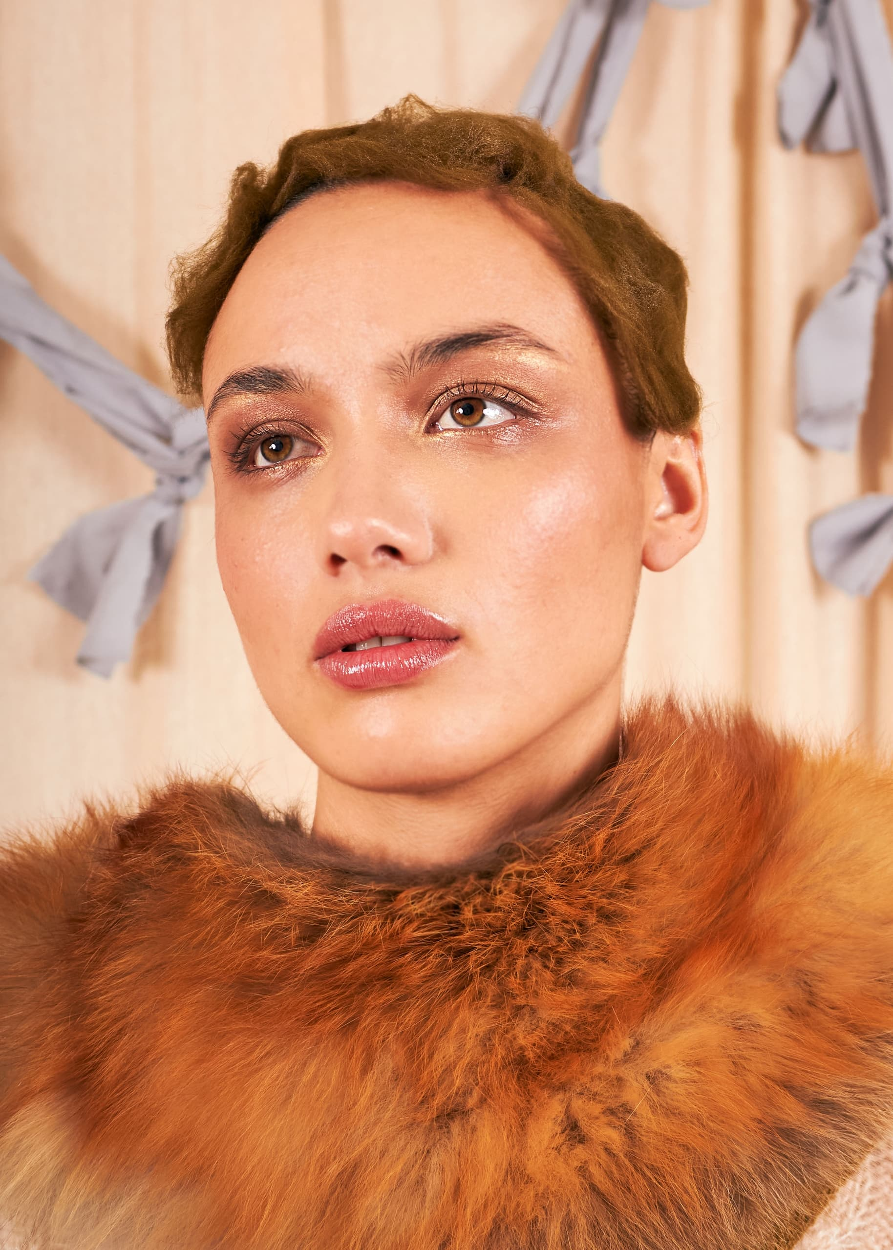 Fashion portrait with fur collar and subtle makeup against a neutral backdrop.