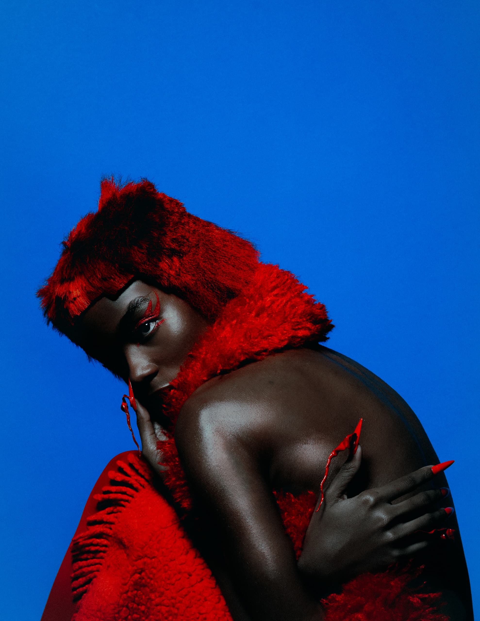 Elegant woman in striking red fur against bold blue background.