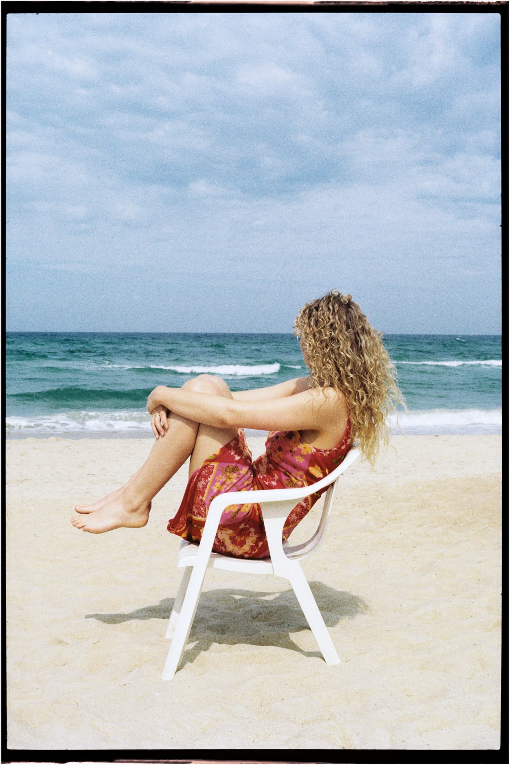 Woman relaxing on a beach chair, enjoying the ocean view under cloudy skies.
