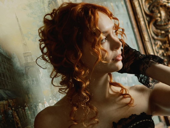 Woman poses elegantly by a vintage painting with ornate frame.