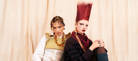 Two models in bold, avant-garde fashion with unique hairstyles and vintage jewelry.