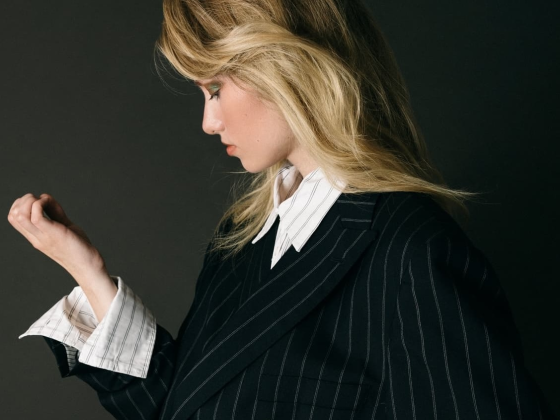 Woman in pinstripe suit with side-swept hair, profile view.