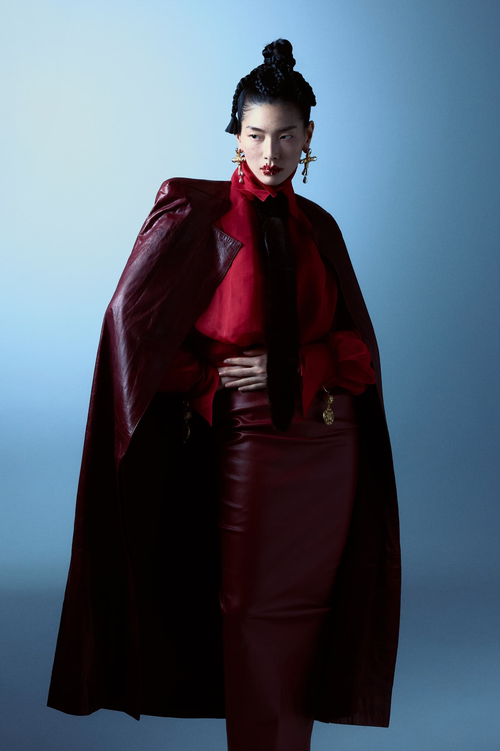 Elegant model in red leather fashion outfit against a blue backdrop.