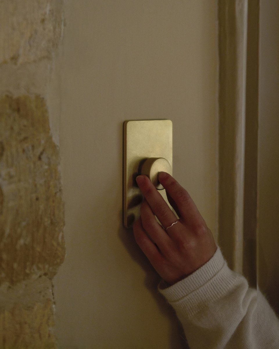 Hand adjusting dimmer switch on wall for cozy lighting.