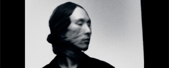 Blurry black and white image of a person in motion, head turned to the side.