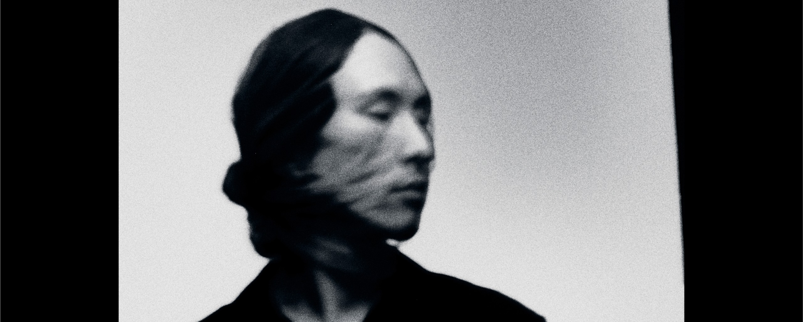 Blurry black and white image of a person in motion, head turned to the side.