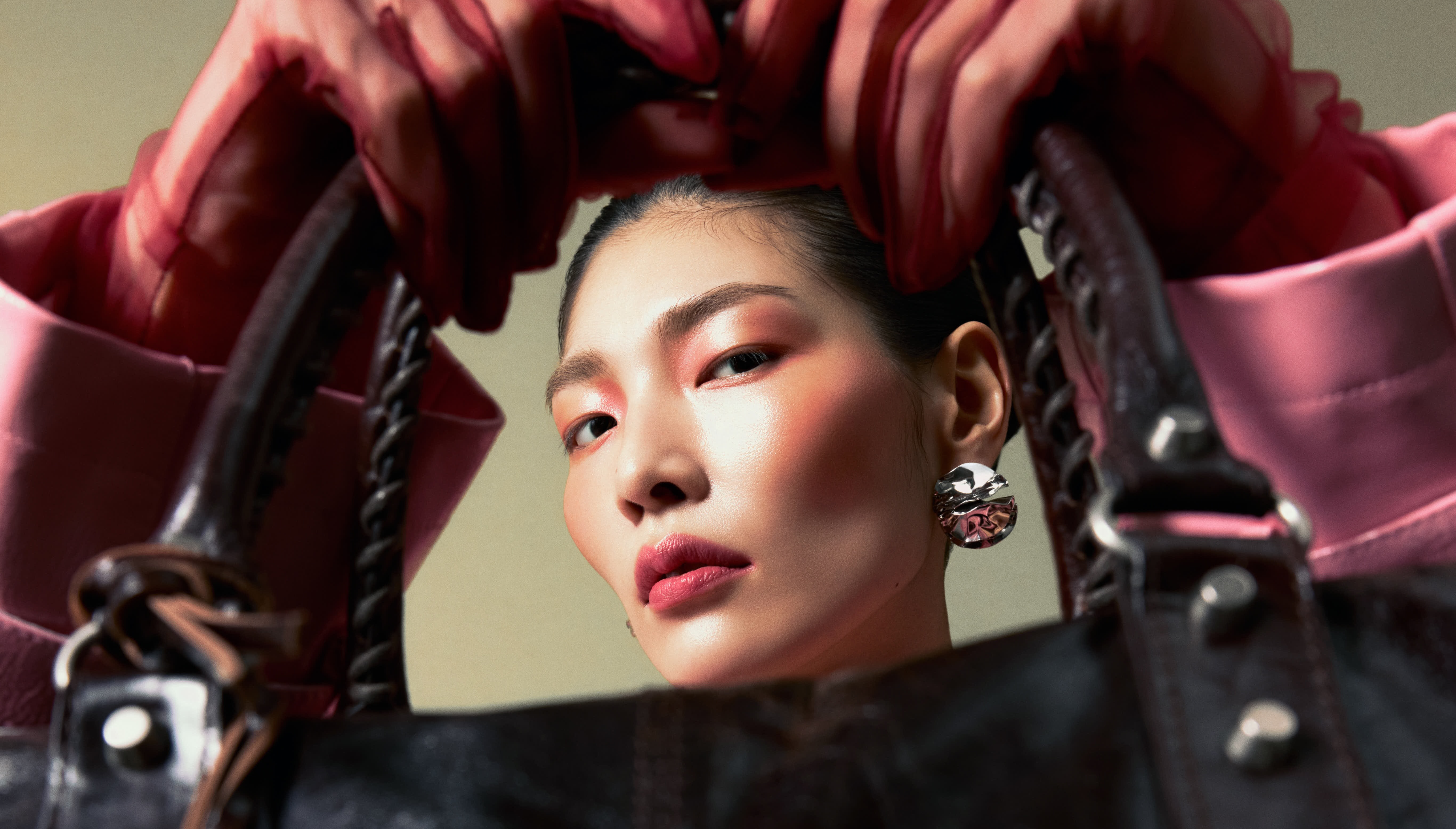 Woman with bold makeup holding stylish leather handbag.