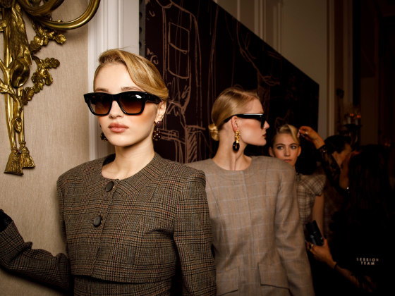 Fashion models in stylish plaid outfits and sunglasses backstage at a show.
