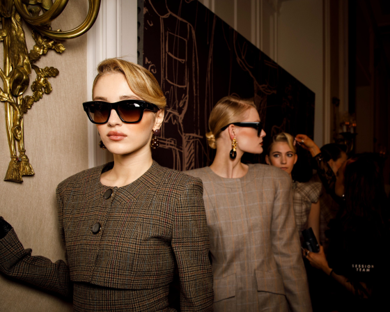 Fashion models in stylish plaid outfits and sunglasses backstage at a show.