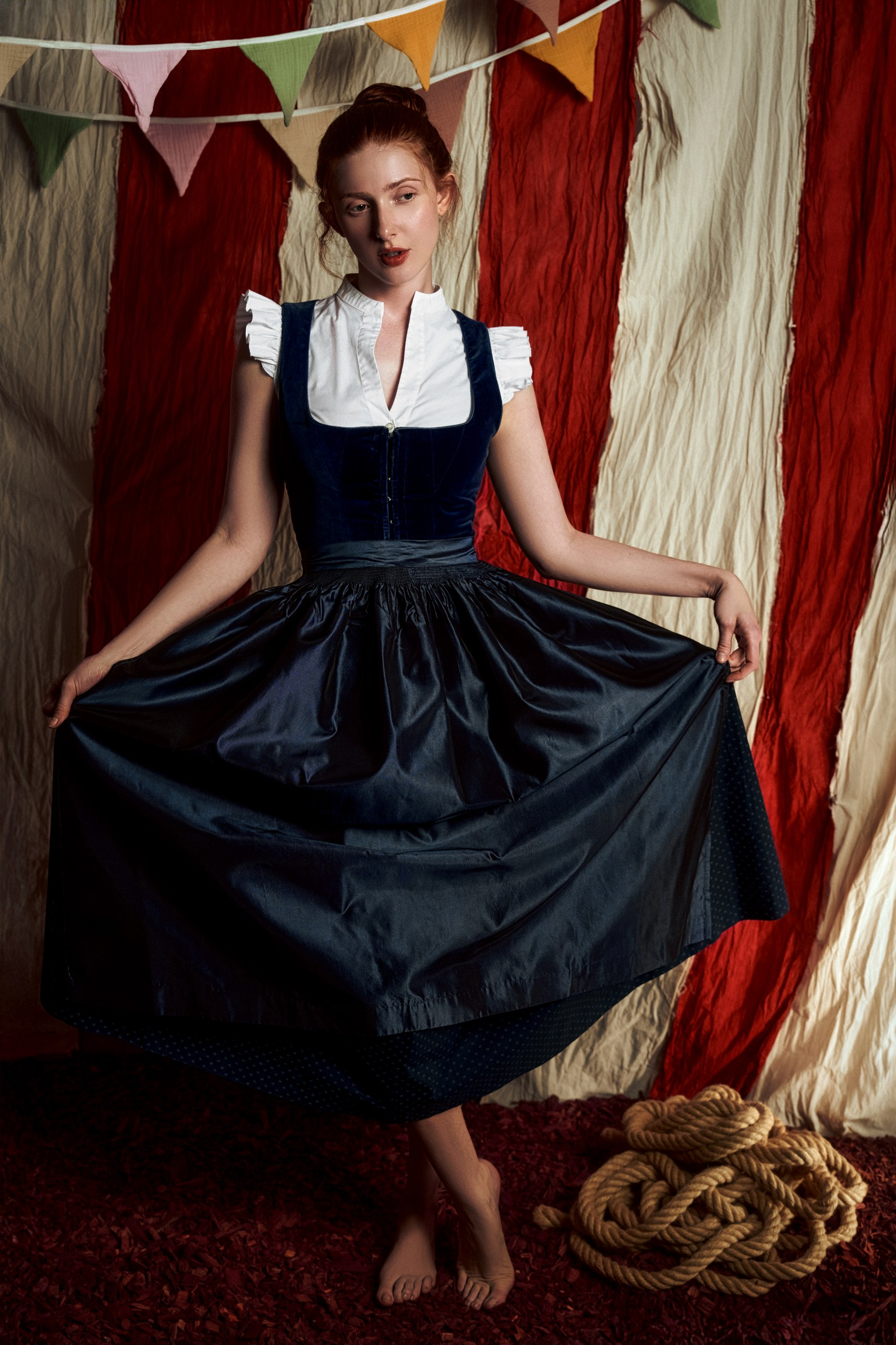 Woman in vintage outfit with colorful bunting and circus-style background.