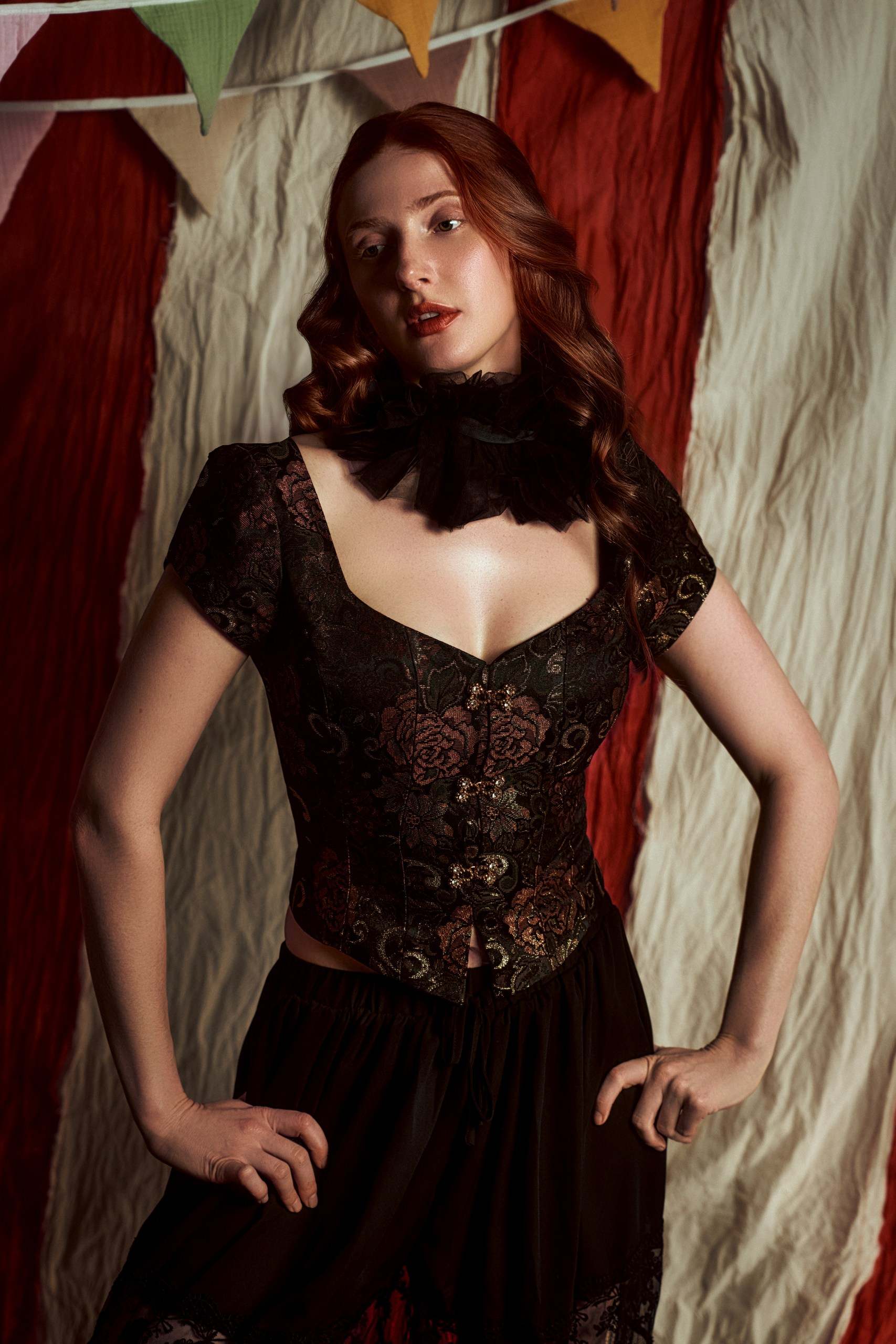 Woman in elegant vintage attire with festive pennant backdrop.