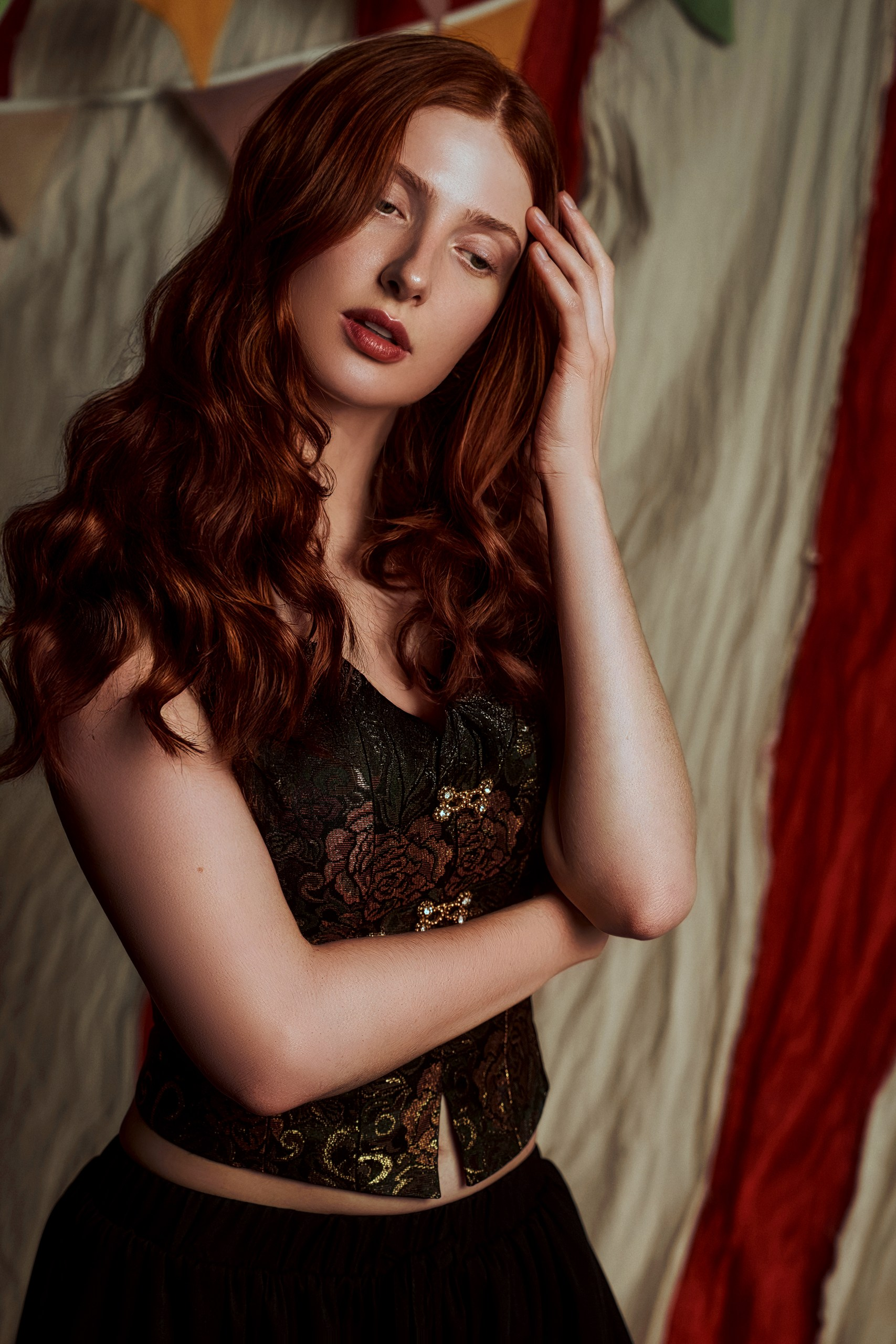 Elegant woman with red hair in a stylish corset, posing gracefully indoors.
