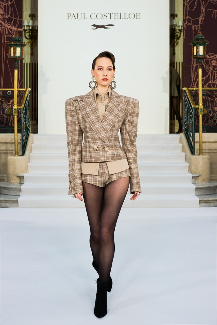 Model in chic plaid suit on runway at fashion show.
