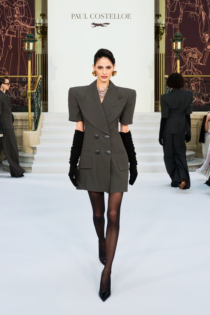 Model in structured blazer dress on runway at Paul Costelloe fashion show.
