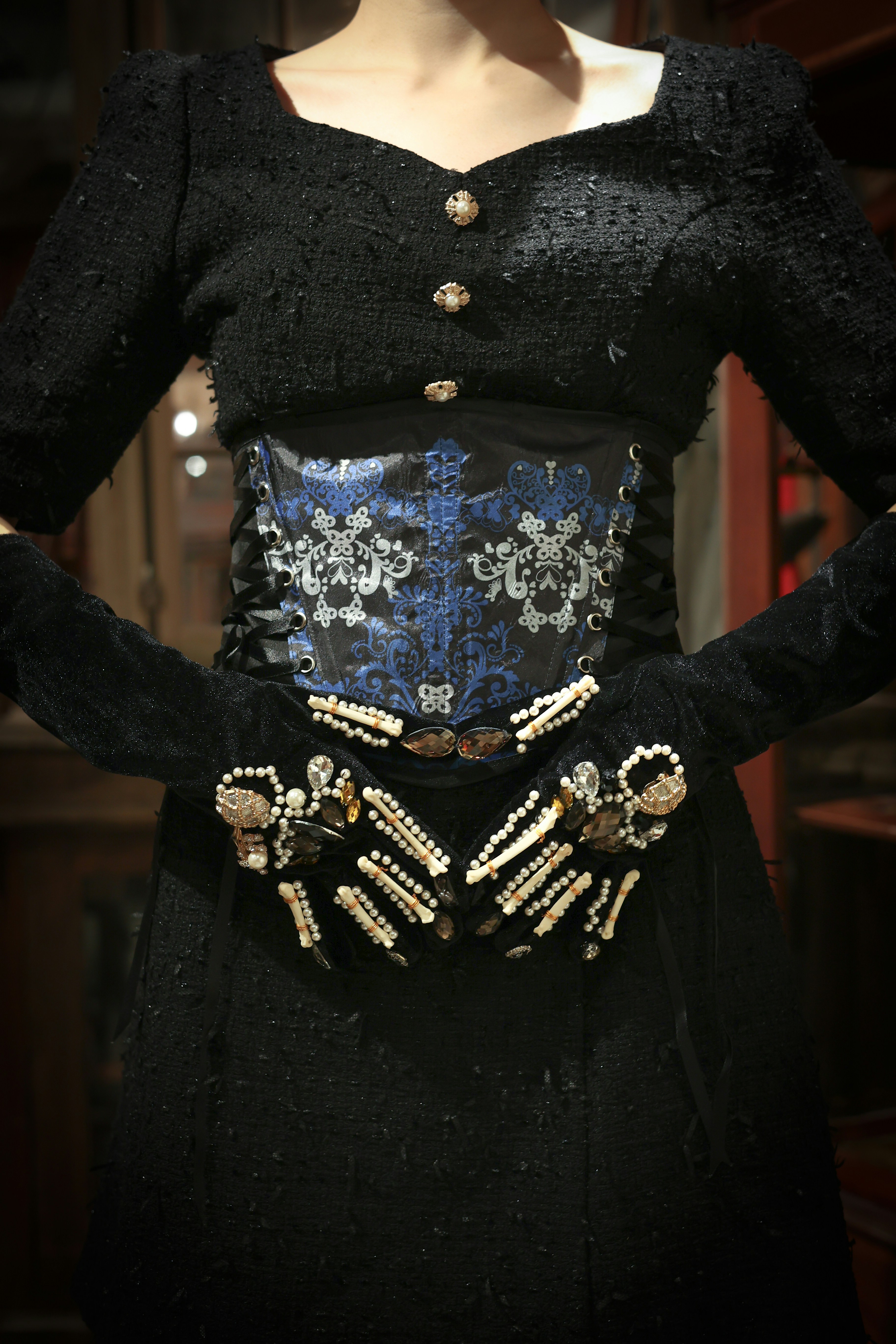 Elegant black dress with jeweled gloves and ornate blue corset design.