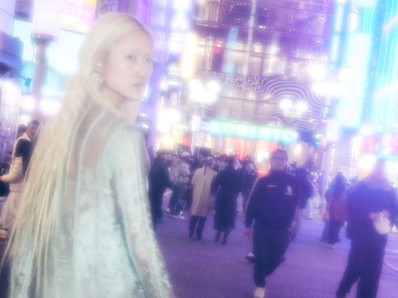 Person walking in vibrant city street at night with neon lights.