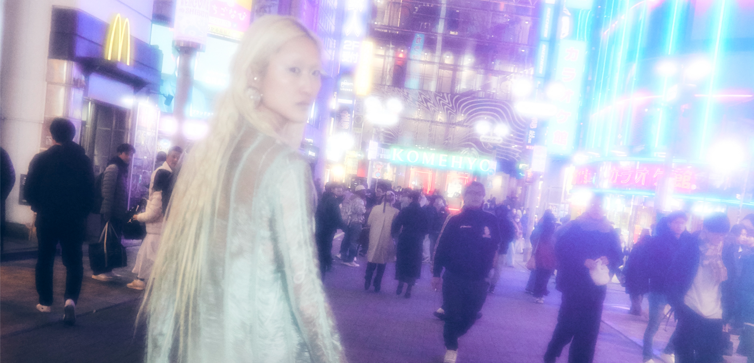 Person walking in vibrant city street at night with neon lights.