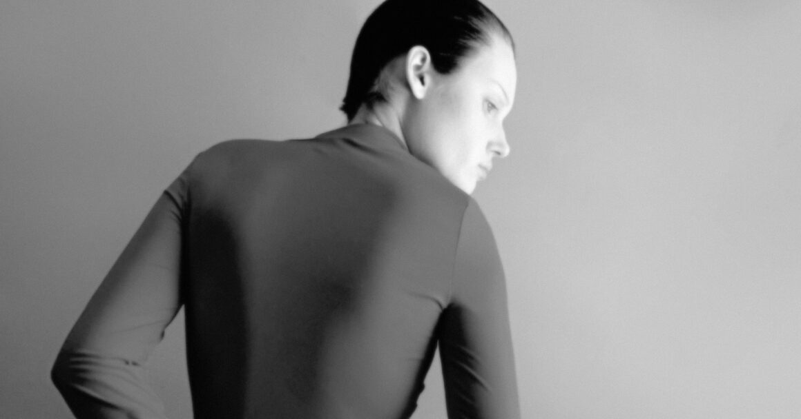 Monochrome portrait of person in sleek attire, gazing thoughtfully to the side.
