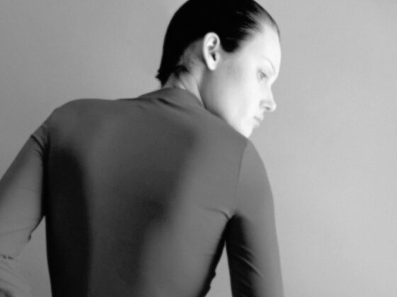 Monochrome portrait of person in sleek attire, gazing thoughtfully to the side.