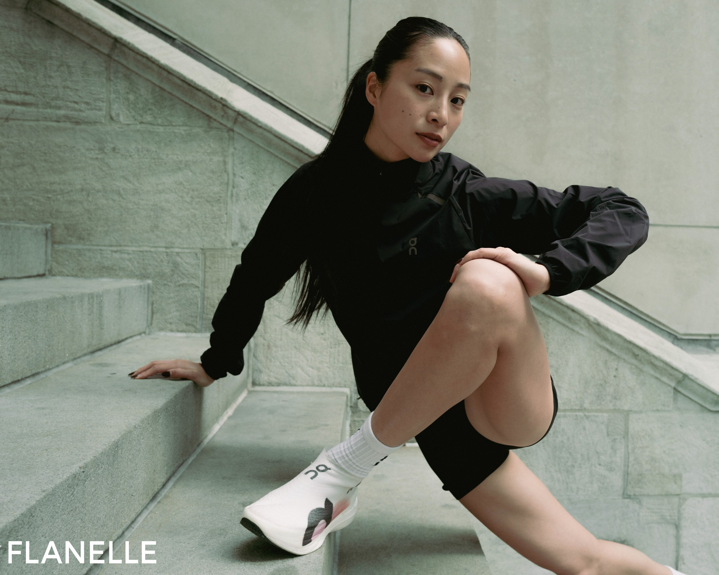 Woman in activewear posing on stairs in a sleek, modern setting.
