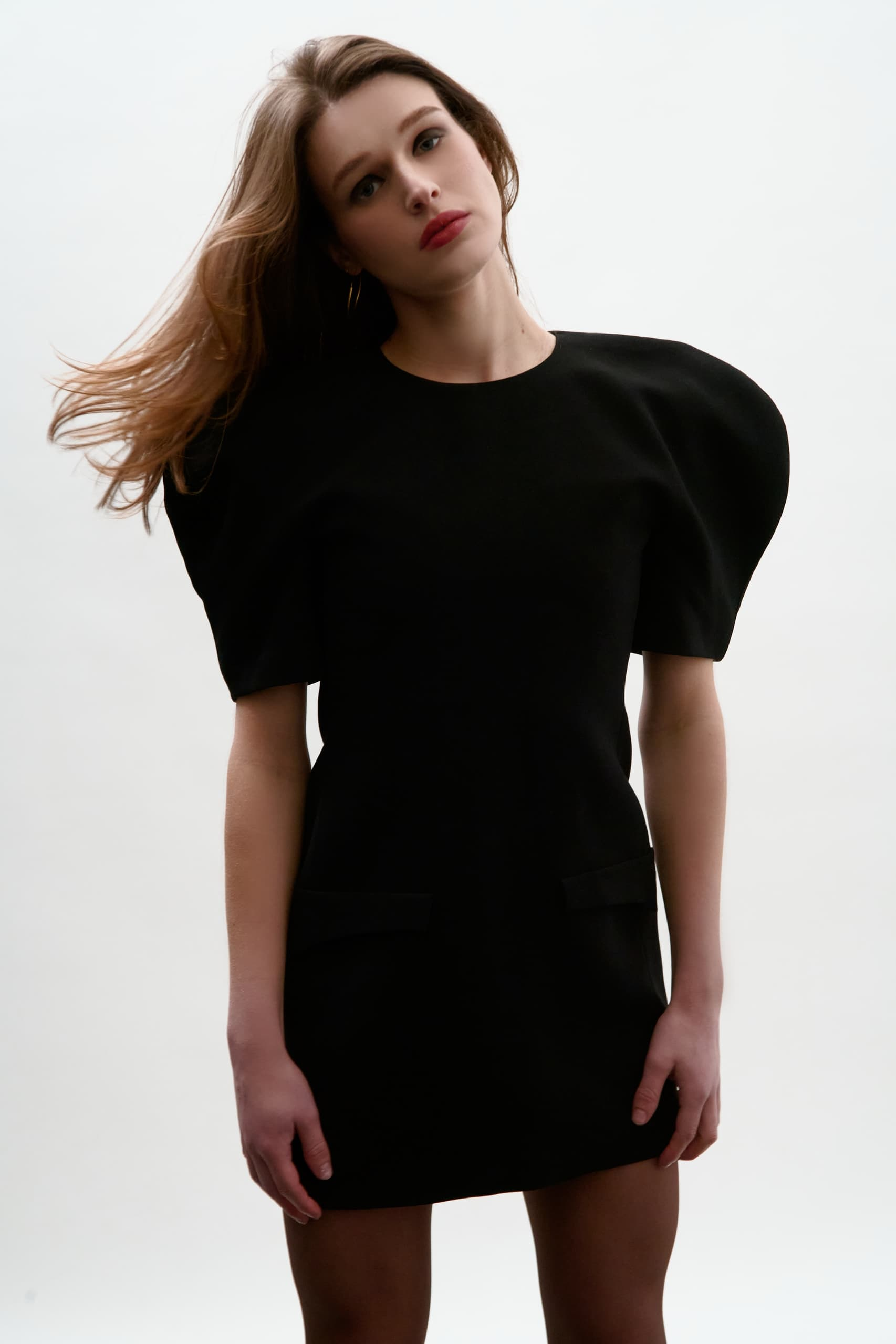 Fashion model in a stylish black dress with puffed sleeves, posing confidently.