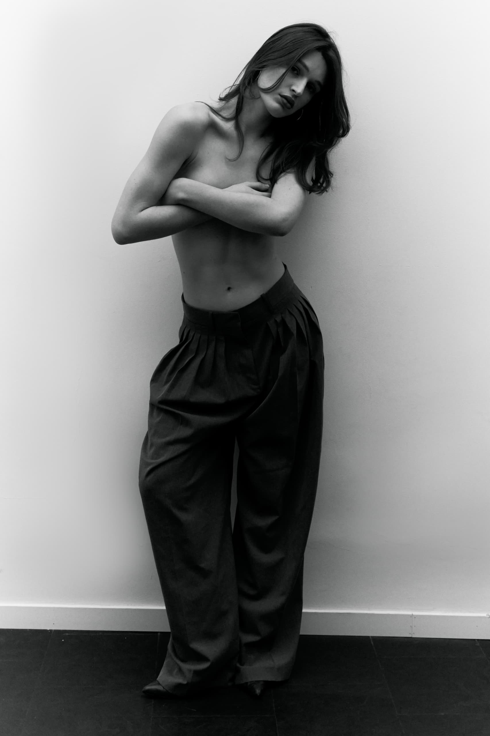 Monochrome portrait of a woman posing confidently in high-waisted trousers.
