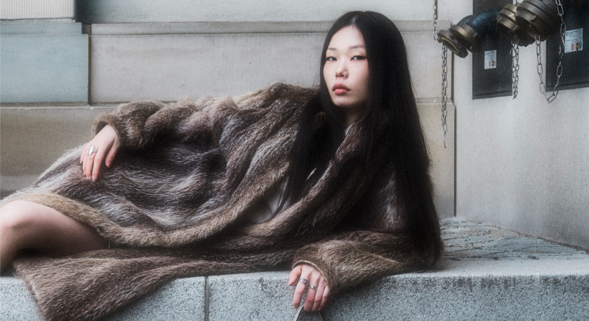 Stylish woman in a fur coat reclining outdoors.
