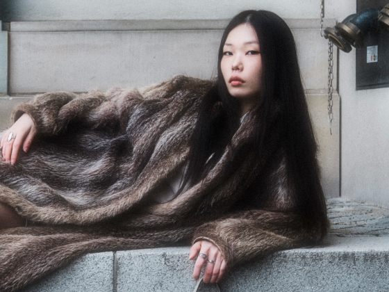 Stylish woman in a fur coat reclining outdoors.