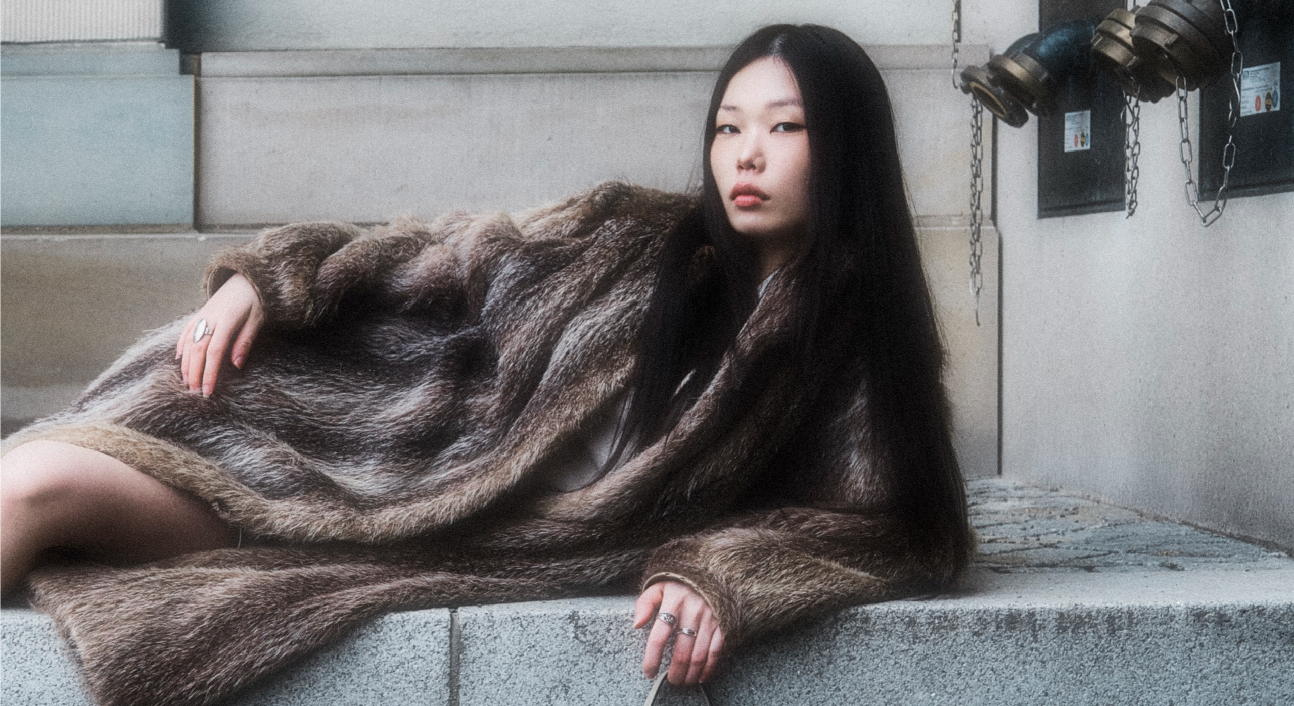 Stylish woman in a fur coat reclining outdoors.