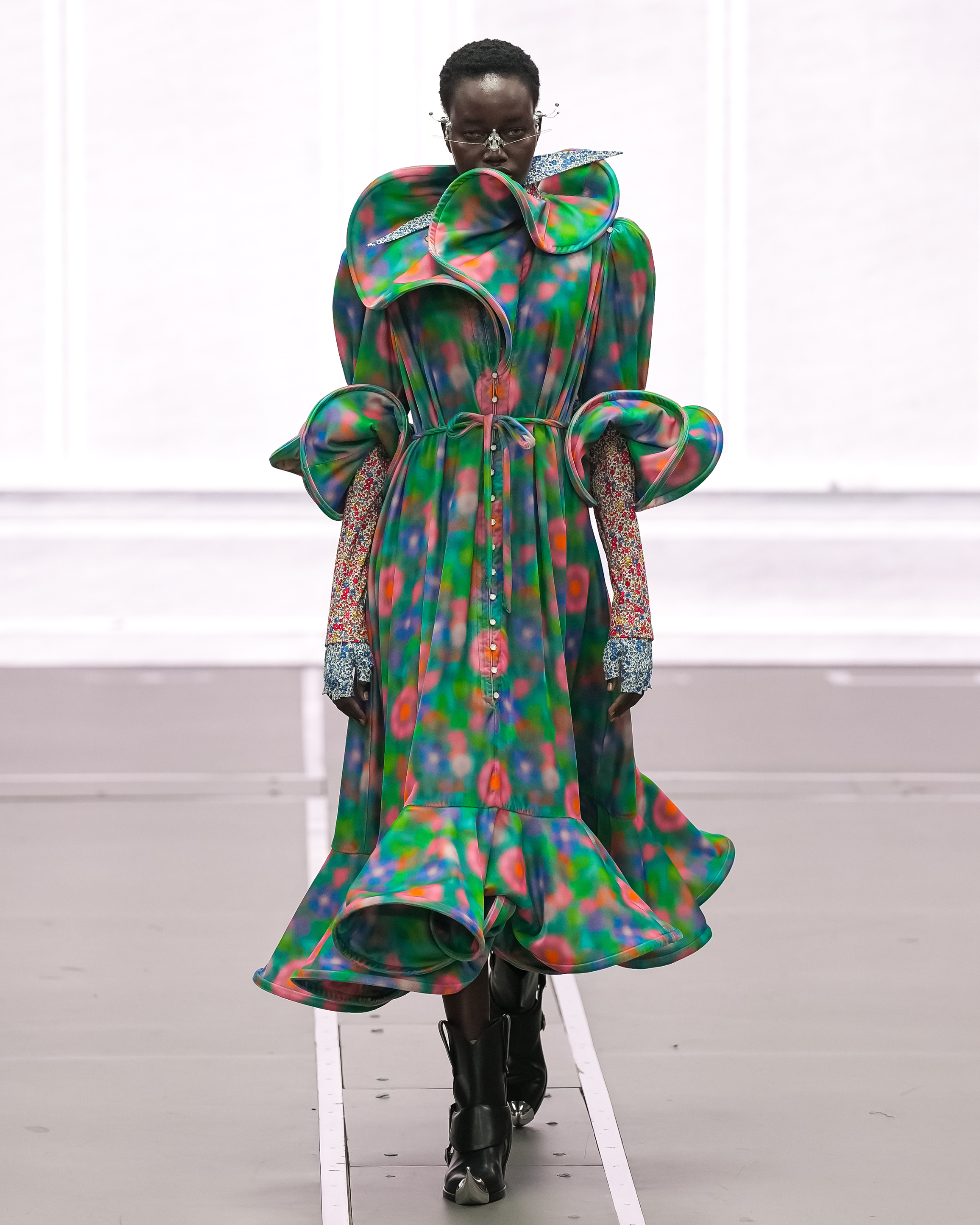 Fashion model in colorful, abstract dress with unique ruffled design on the runway.