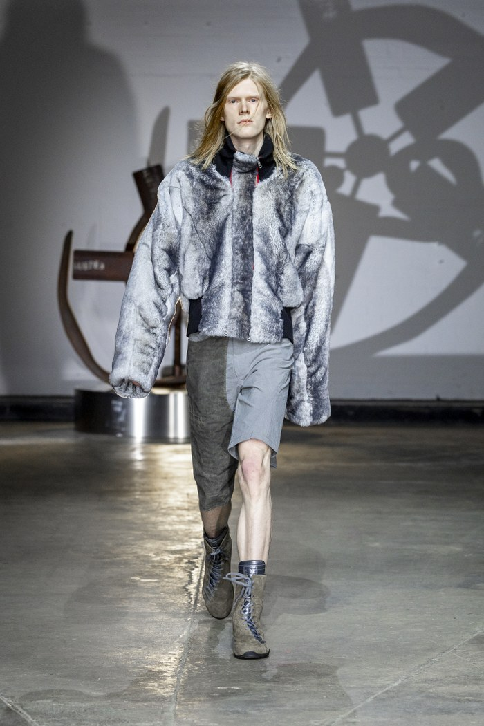 Model wearing a fur jacket and shorts on the runway.