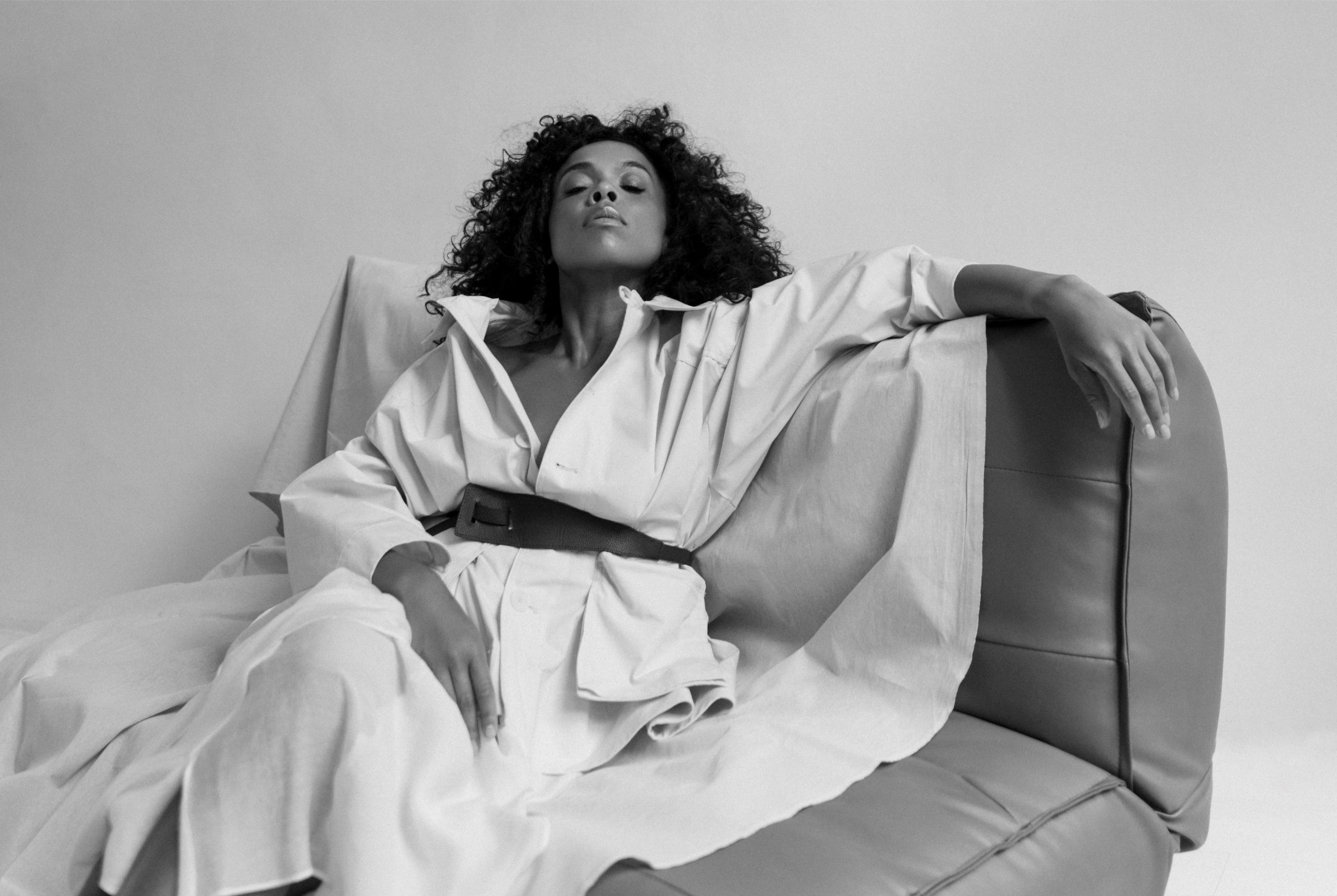Chic woman lounging on a couch in a stylish outfit, exuding confidence and elegance.