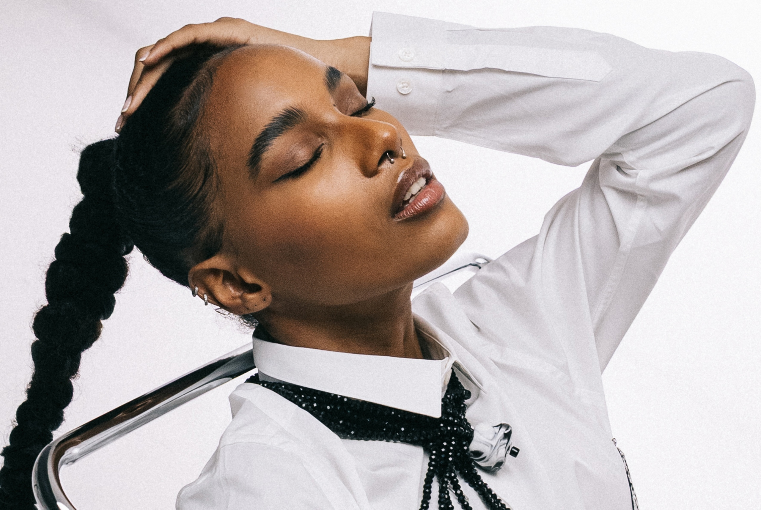 Fashion portrait of a person in a white shirt posing with eyes closed.
