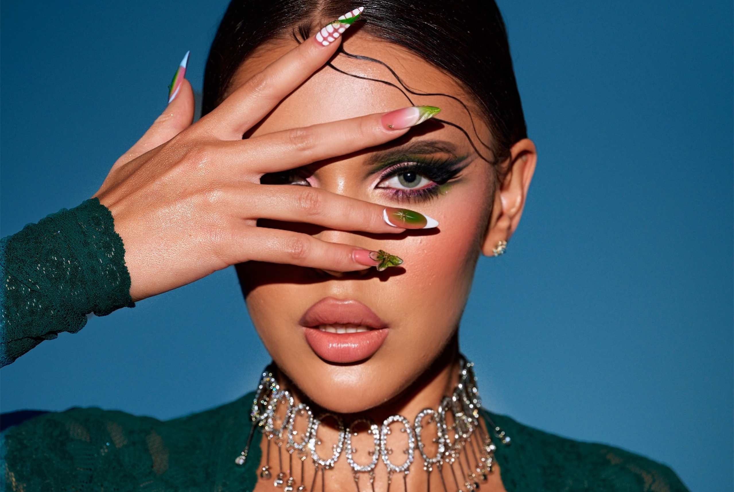 Chic woman with bold eye makeup, artistic nails, and intricate jewelry.