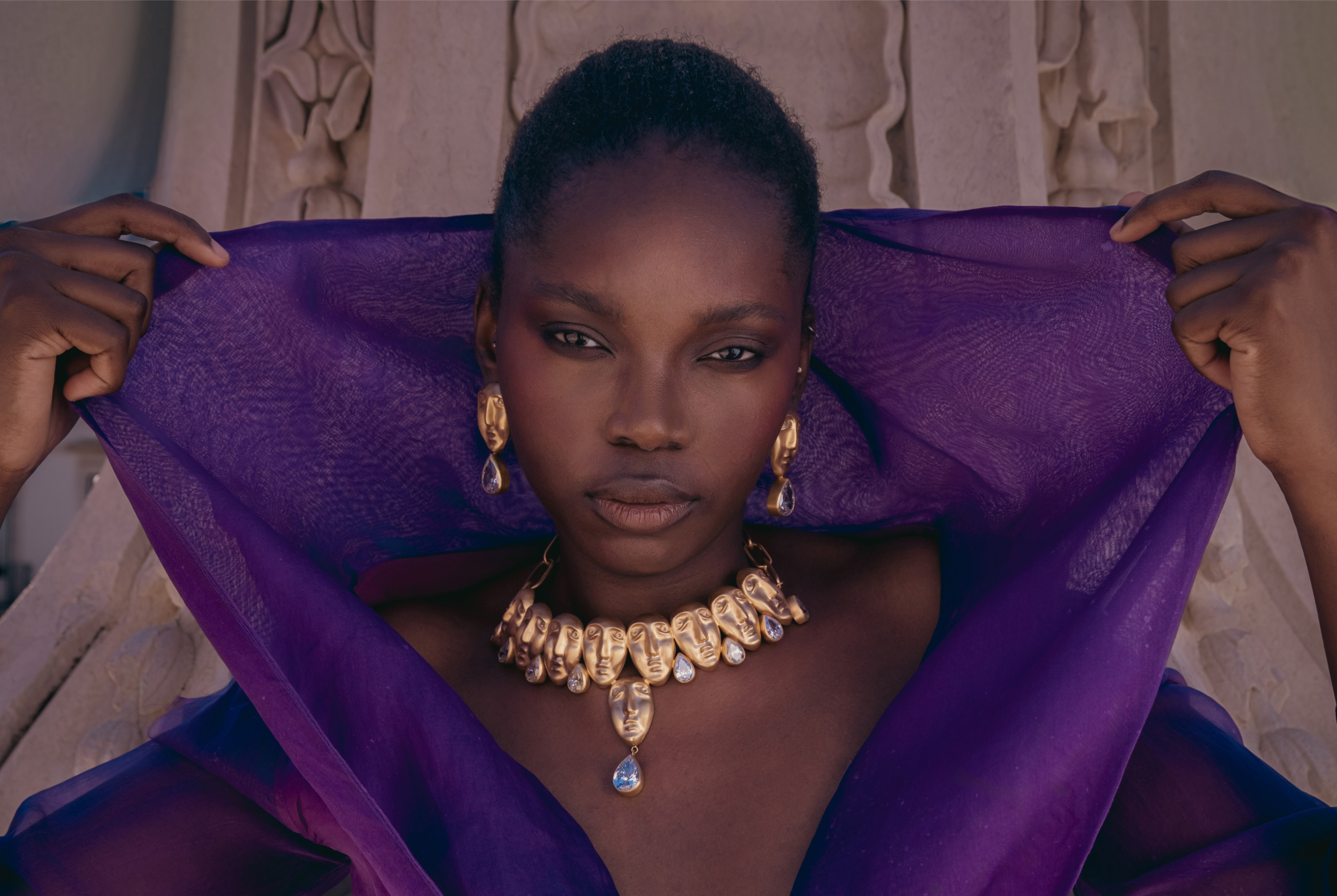 Woman in purple veil, gold jewelry; elegant fashion portrait.