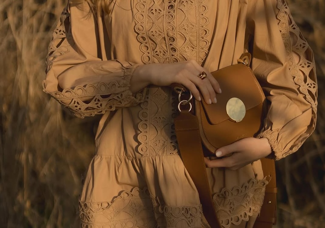 Elegant lace dress and chic tan purse in stylish autumn setting.
