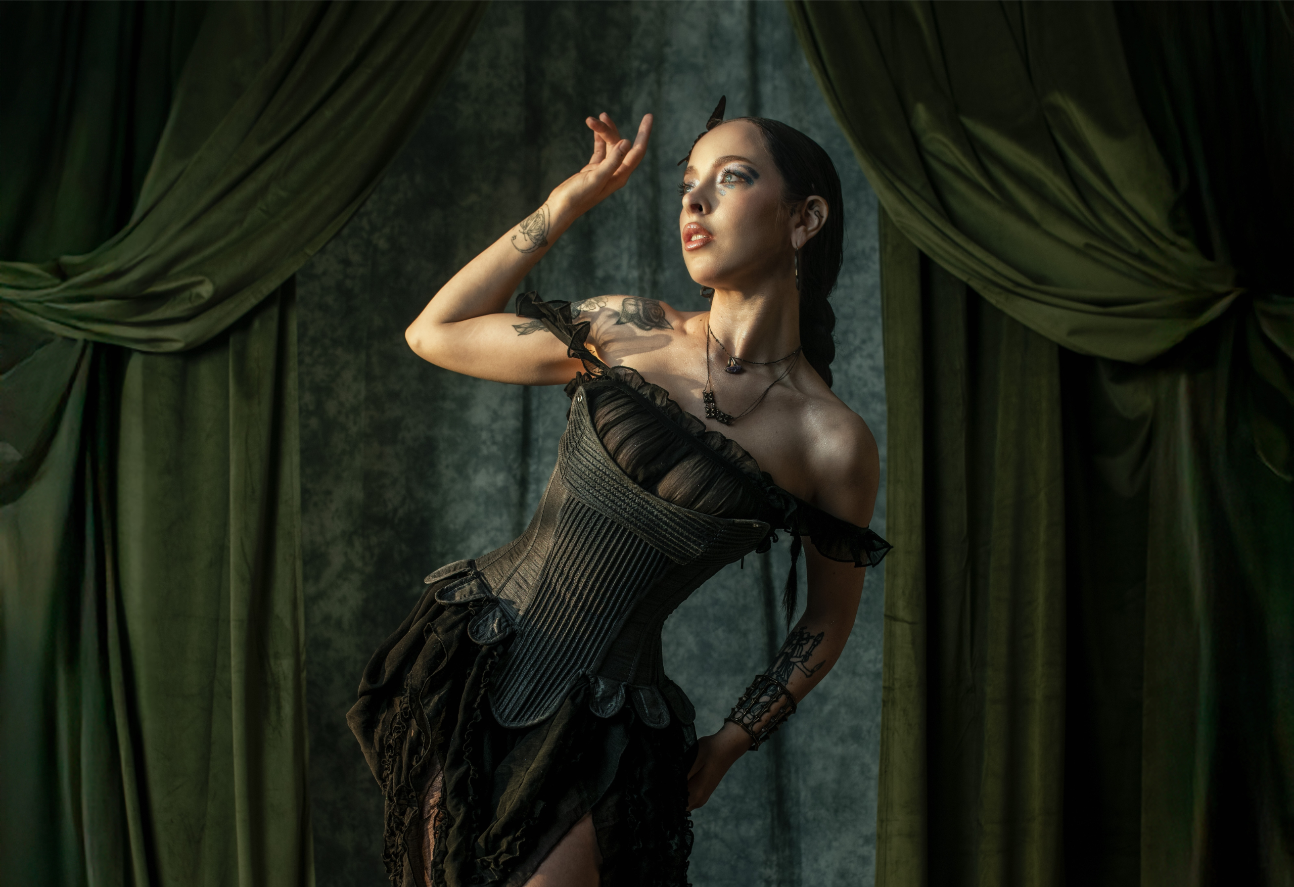 Elegant woman in corset posing with dramatic lighting and green curtains.