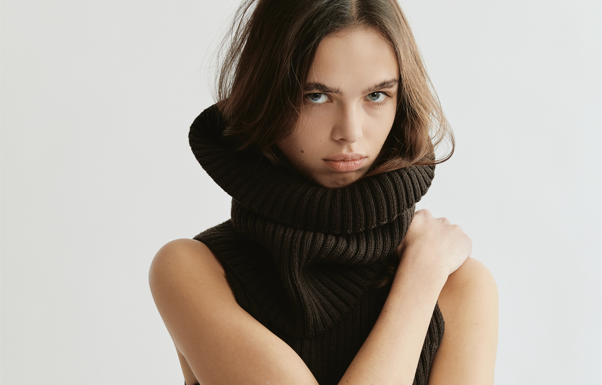 Woman in a cozy, dark knit sweater against a light background.